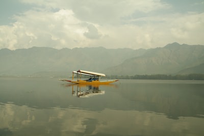 Yellow boat on the water, the day in the white and gray sky to watch the mountain
